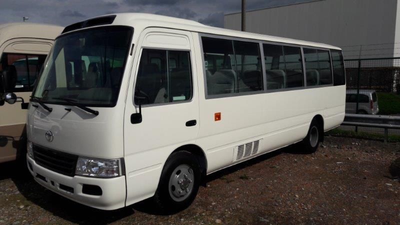 Minibus Toyota Coaster blanc, vue trois quarts avant